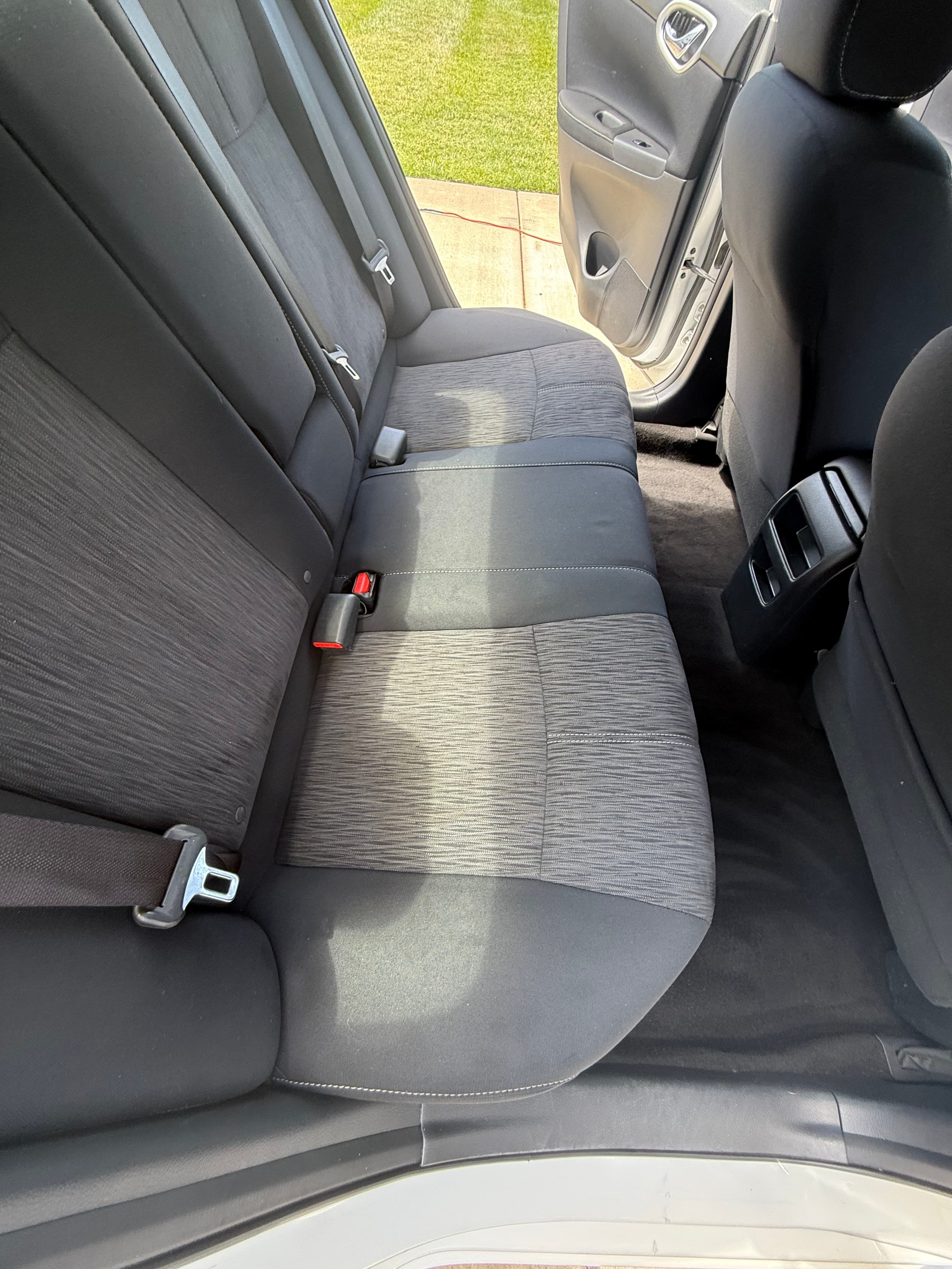 Overhead view of a car's rear bench seat upholstered in dark grey textured fabric.